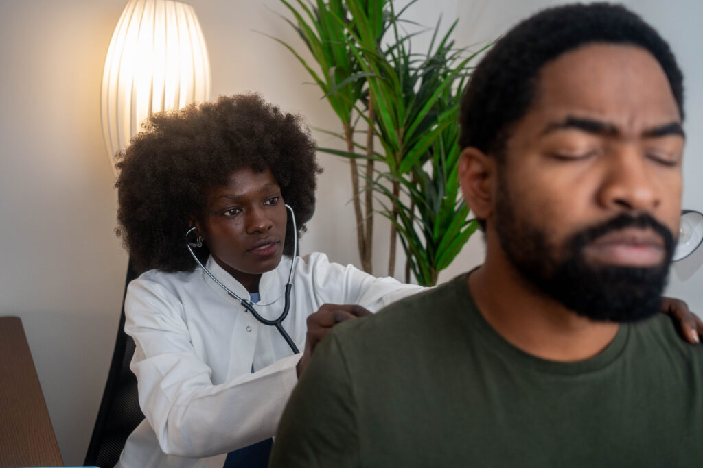 Doctor listening to patient’s heart with stethoscope in clinic, providing medical care.